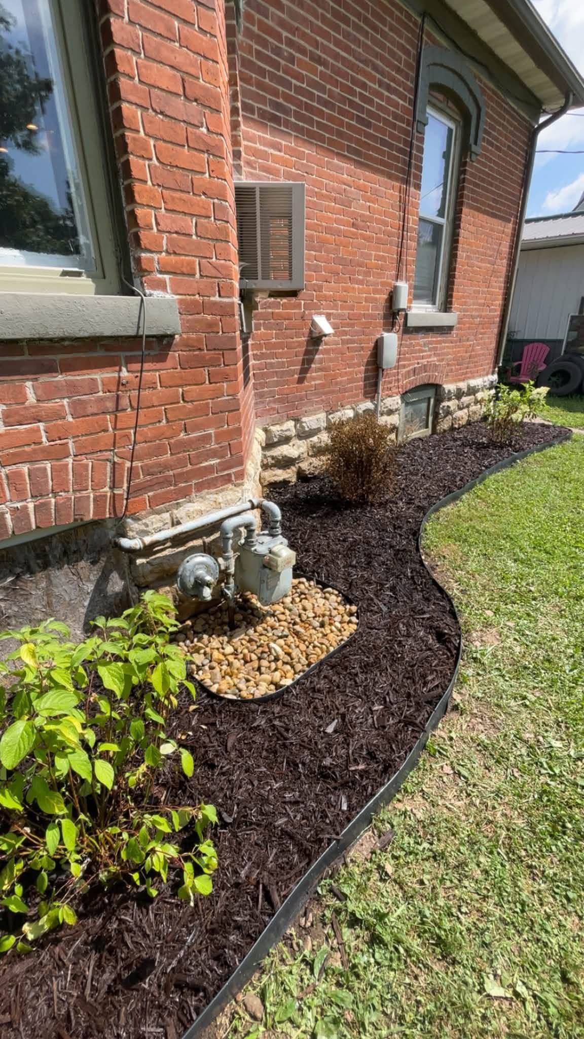 Finished landscaping and mulch installation beside a Waukon-area home